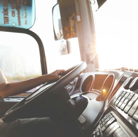 A bus driver navigating the city streets during a sunny day, focusing on the road.